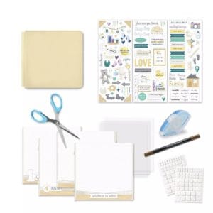 A display of the Creative Memories 8x8 lemon ice welcome baby kit. It includes the lemon ice album cover, three sheets of stickers, all purpose scissors, pre-printed pages, page protectors, a tape runner, dual-tip pen, and foam squares.